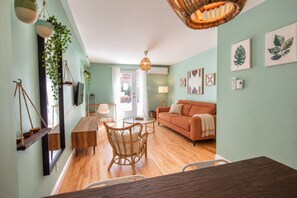 A living room with a sofa, a dining table, and a hanging plant. - Bohemian/2Bds/Rooftop/Terraces/Plateau/St-Denis/AC (Montréal)