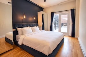 A modern bedroom with a large bed, a dark headboard, and a view of the outdoors through a sliding glass door. - Vintage/Rooftop/Terraces/Plateau/St-Denis/AC/TV (Montréal)