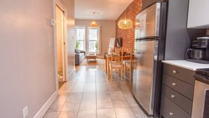 A modern kitchen with a stainless steel refrigerator, a coffee maker, and a dining area with a table and chairs. - Zen/Rooftop/Terraces/Plateau/St-Denis/AC/TV (Montréal)