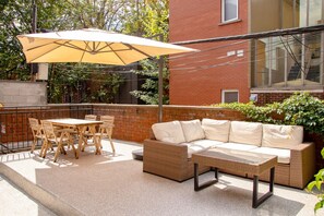 An outdoor patio with a table and chairs, a sofa, and a large umbrella. - Zen/Rooftop/Terraces/Plateau/St-Denis/AC/TV (Montréal)