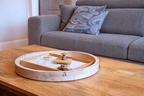 A wooden tray with a model of a traditional Japanese tea ceremony setup on a wooden table in a living room.