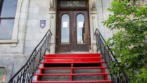 Un edificio con fachada de piedra, una escalera roja y una puerta doble con el número 3600.