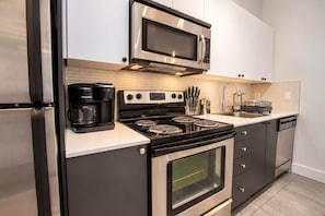 Une cuisine moderne équipée d’un réfrigérateur en acier inoxydable, d’un four à micro-ondes encastré, d’une machine à café Keurig, d’une cuisinière et d’un lave-vaisselle.