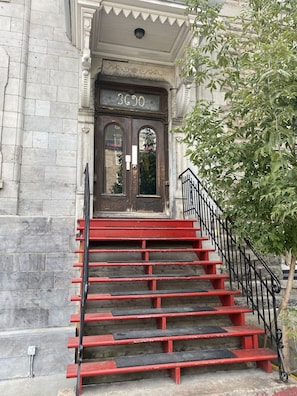 Une entrée d’immeuble avec un escalier rouge menant à une porte portant l’inscription « 3030 ».