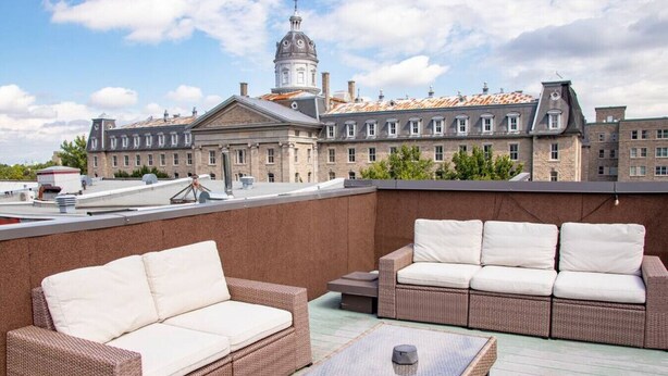 Terraza en la azotea con mobiliario de mimbre y vistas a un edificio histórico con cúpula.