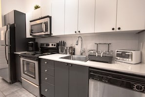 Une cuisine moderne équipée d’un four à micro-ondes, d’une cuisinière et d’un lave-vaisselle intégrés.