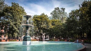 Una fuente circular de varios niveles, rodeada por un camino empedrado.