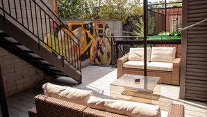 A patio with wicker furniture, a glass table, and a staircase with a mural. - Pop/Rooftop/Terraces/Plateau/St-Denis/AC/TV (Montréal)