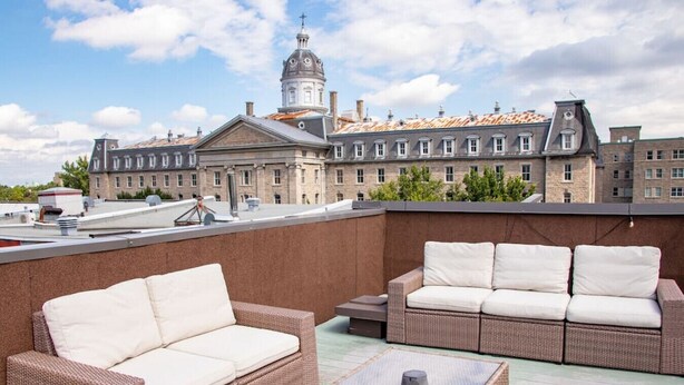 A rooftop terrace with wicker furniture and a view of a historic building with a dome. - Gatsby/Rooftop/Terraces/Plateau/St-Denis/AC/TV (Montréal)