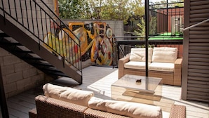A patio with wicker furniture, a glass table, and a staircase with a mural. - Gatsby/Rooftop/Terraces/Plateau/St-Denis/AC/TV (Montréal)