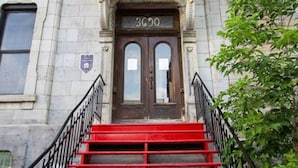 A building entrance with a red staircase, a double door, and a small balcony with white railings. - Gatsby/Rooftop/Terraces/Plateau/St-Denis/AC/TV (Montréal)