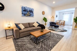 A modern living room with a sofa, coffee table, and a painting on the wall. - Blue&Gold/Plateau/St-Laurent/SelfCheck-In/AC/TV (Montréal)