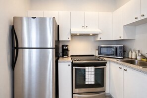 A modern kitchen with stainless steel appliances, including a refrigerator, microwave, and oven. - Blue&Gold/Plateau/St-Laurent/SelfCheck-In/AC/TV (Montréal)