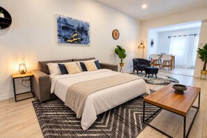A modern bedroom with a bed, bedside tables, a coffee table, and a dining area with chairs.