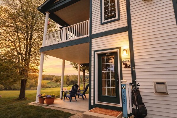 A two-story house with a porch, a door with a number, and a welcome sign.