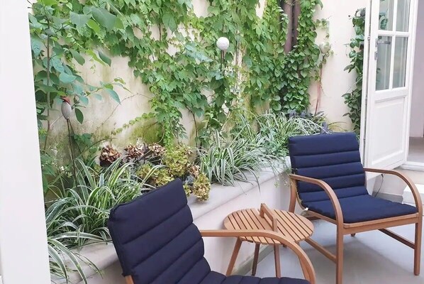 Relax in this serene outdoor seating area with comfortable chairs and a charming garden view.
