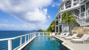 A pool with a white deck and lounge chairs, overlooking the ocean. - Unrivaled Oceanfront Views In Our Private Caribbean Resort (St Thomas)