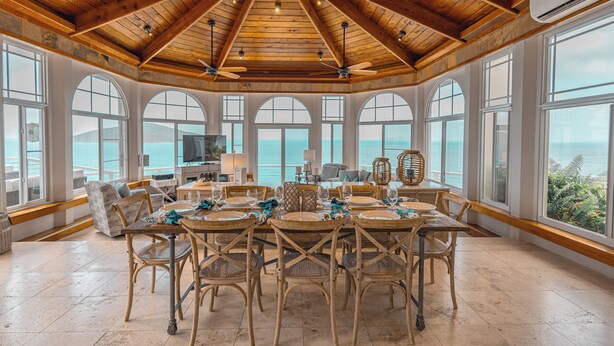 A spacious dining area with a high wooden ceiling, large arched windows, and a view of the ocean. - Unrivaled Oceanfront Views In Our Private Caribbean Resort (St Thomas)