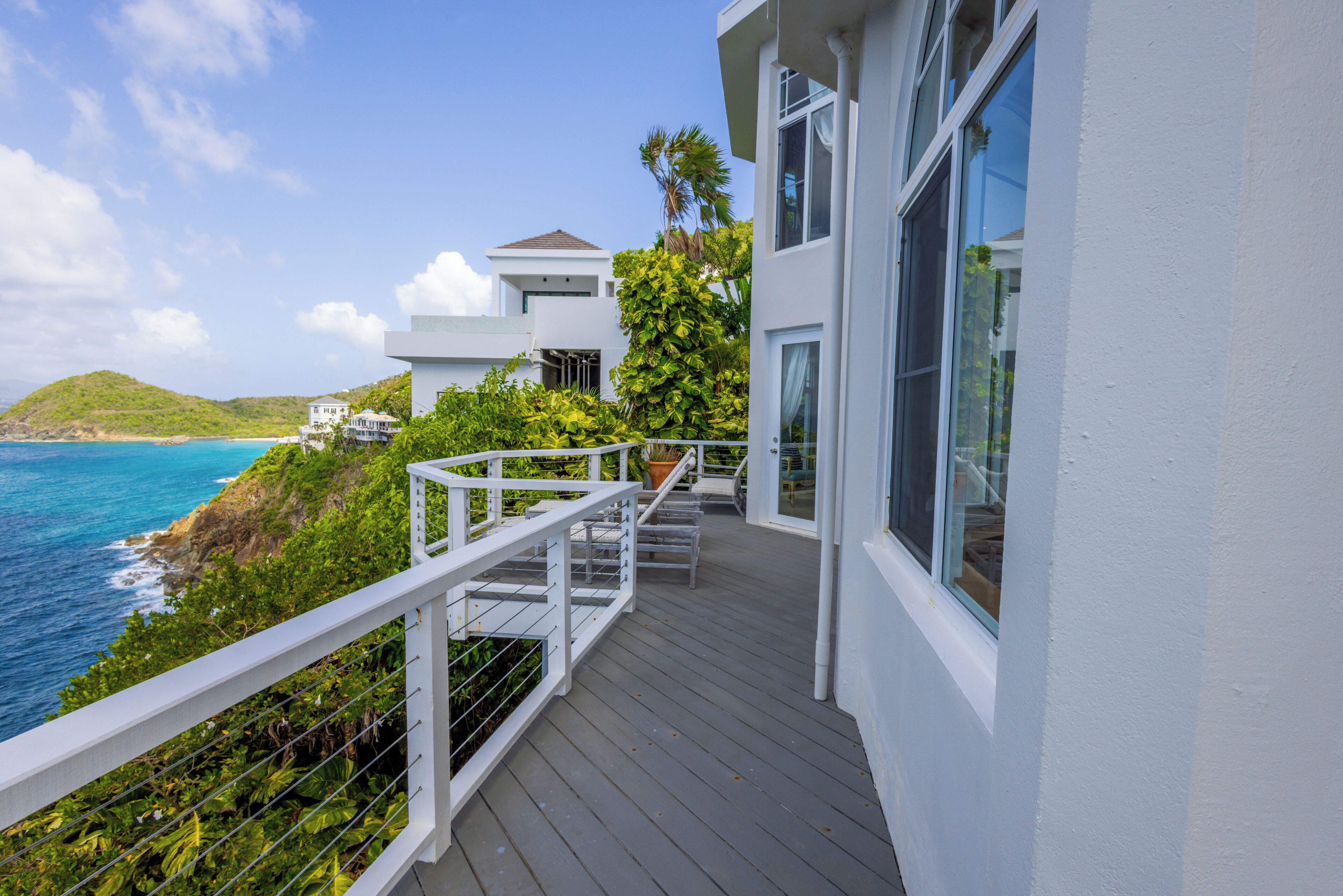 A balcony with a view of the ocean and a white building with large windows.