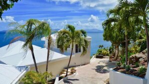 A coastal property with a white building, palm trees, and a view of the ocean. - Unrivaled Oceanfront Views In Our Private Caribbean Resort (St Thomas)
