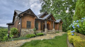 A log cabin with stone foundation, wooden exterior, and a stone pathway leading to the entrance.