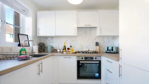 A modern kitchen with white cabinets, a built-in oven, and a countertop with various appliances. - Welcoming House with Free Parking and Fast WiFi (Luton)