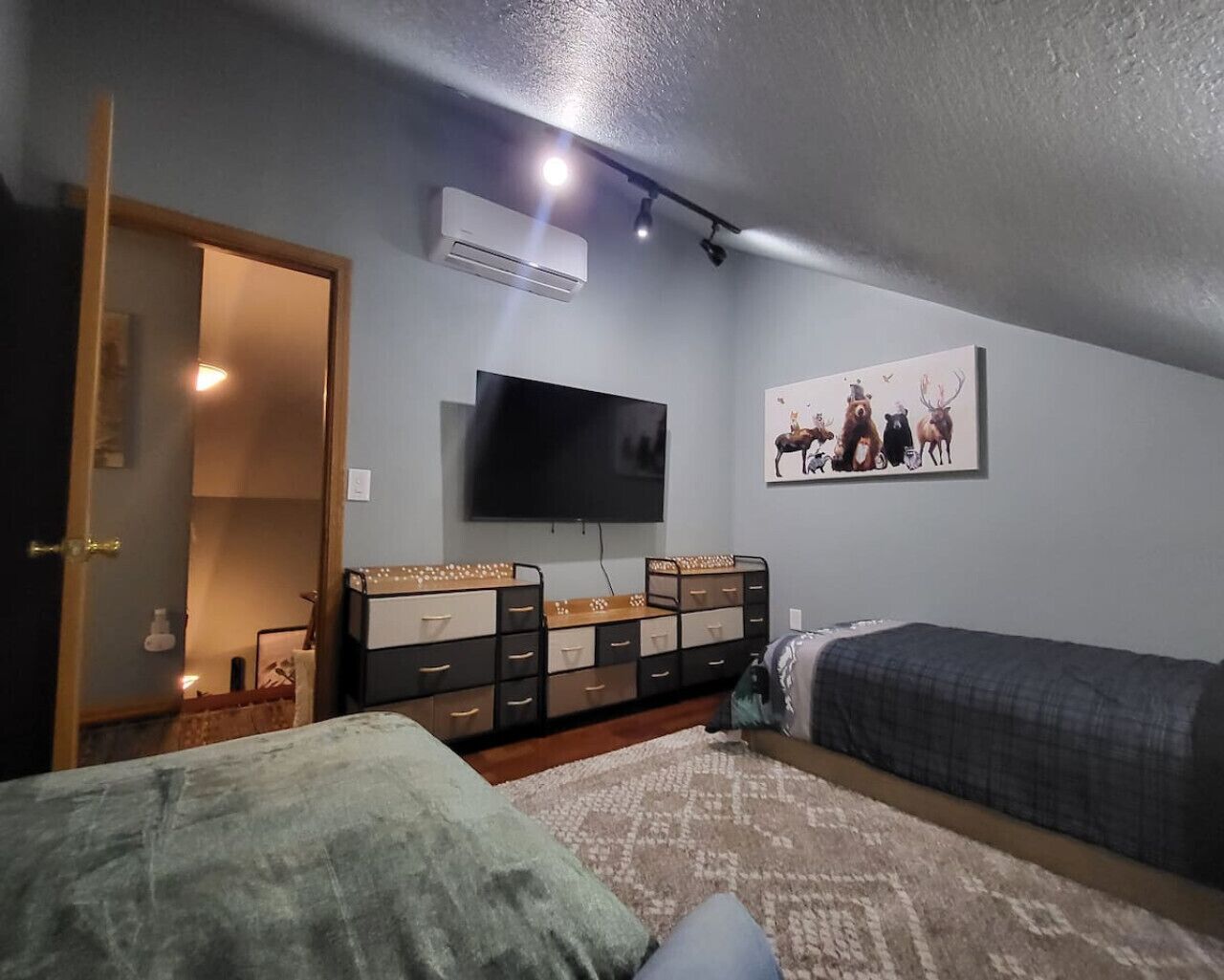 Ein Schlafzimmer mit einem Bett, einem Schminktisch, einem Fernseher und einer Wand-Klimaanlage.