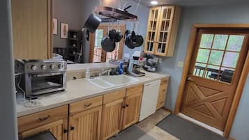A kitchen with wooden cabinets, a built-in oven, a sink, and hanging pots.