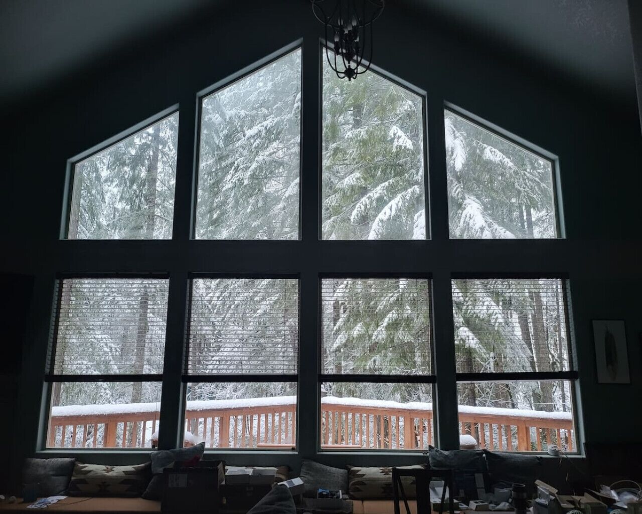 A room with large windows offering a view of a snowy forest.