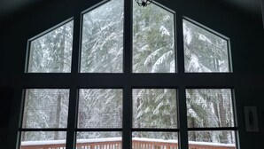 Una habitación con amplios ventanales que dan a un bosque nevado.