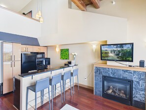 Eine moderne Küche mit Barbereich, Kamin und Flachbildfernseher.