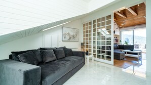 A modern living room with a dark grey sofa, a white coffee table, and a large window with a view of the outdoors.