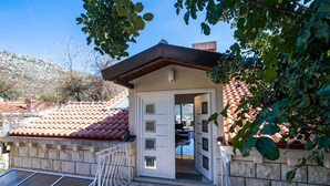 A stone building with a tiled roof, a door, and a small patio area.