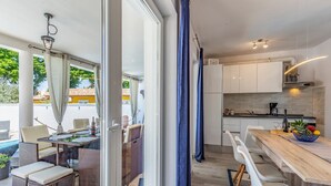 Une cuisine moderne avec des meubles blancs, un plan de travail en bois et un coin repas doté de meubles en osier.