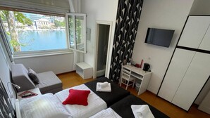 Hotellihuone, jossa on kaksi sänkyä, työpöytä, televisio ja näkymä vesistölle.