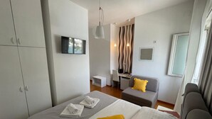 A modern hotel room with a bed, a desk, a sofa, and a TV.