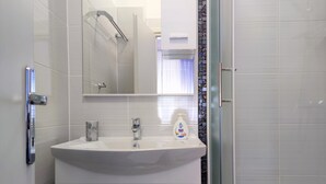 A bathroom with a white sink, a mirror, and a shower area.