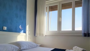 A hotel room with a bed, a window with blinds, a wall with a butterfly sticker, and a towel on the bed. - 3. Double room with sea view (Zadar)