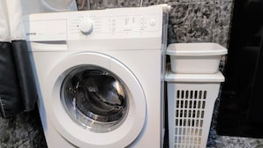 A front-loading washing machine with a control panel, a white laundry basket, and a vent.