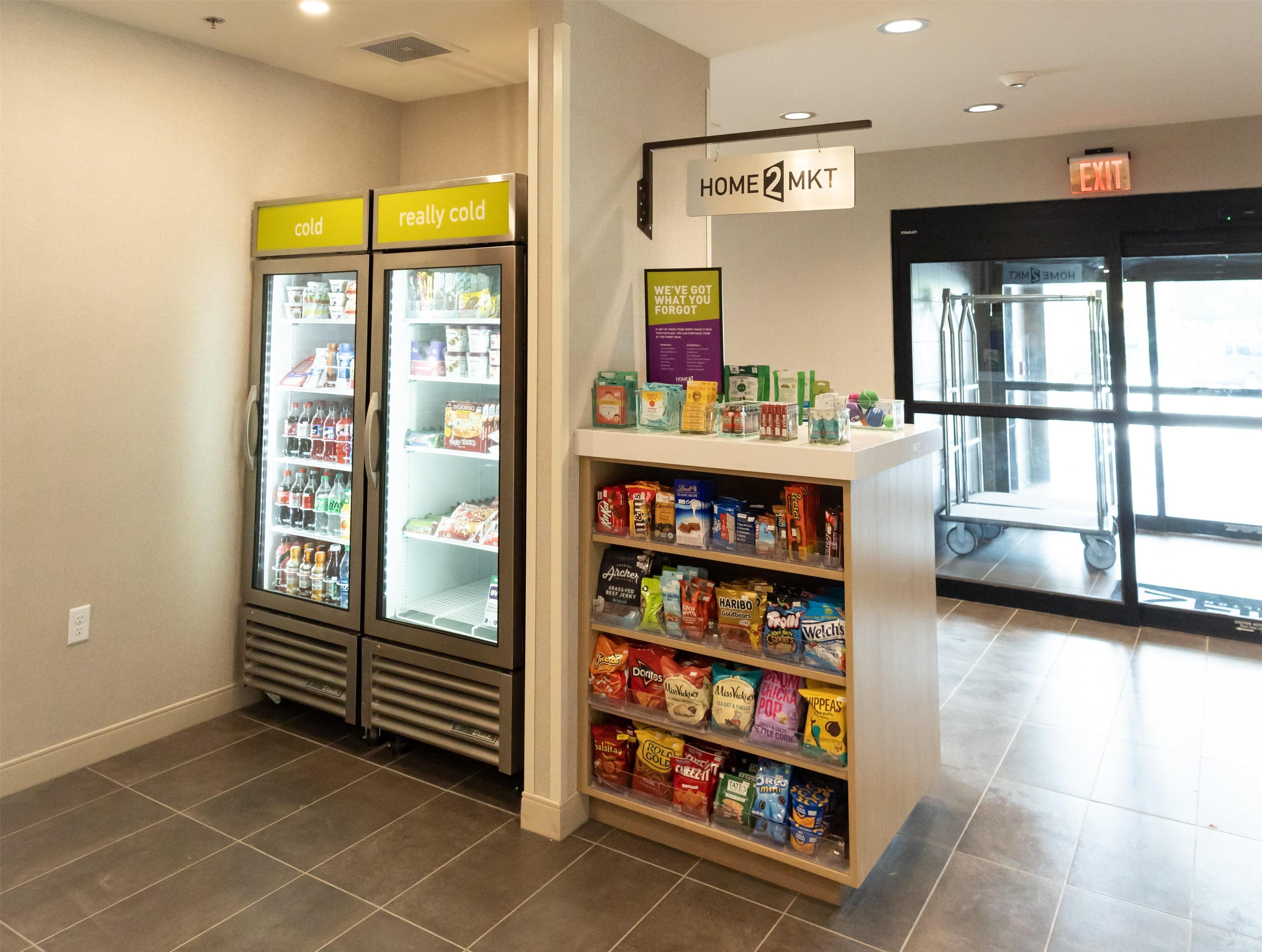 Un magasin Home2MKT doté de distributeurs de boissons réfrigérés et d’une étagère remplie d’en-cas.