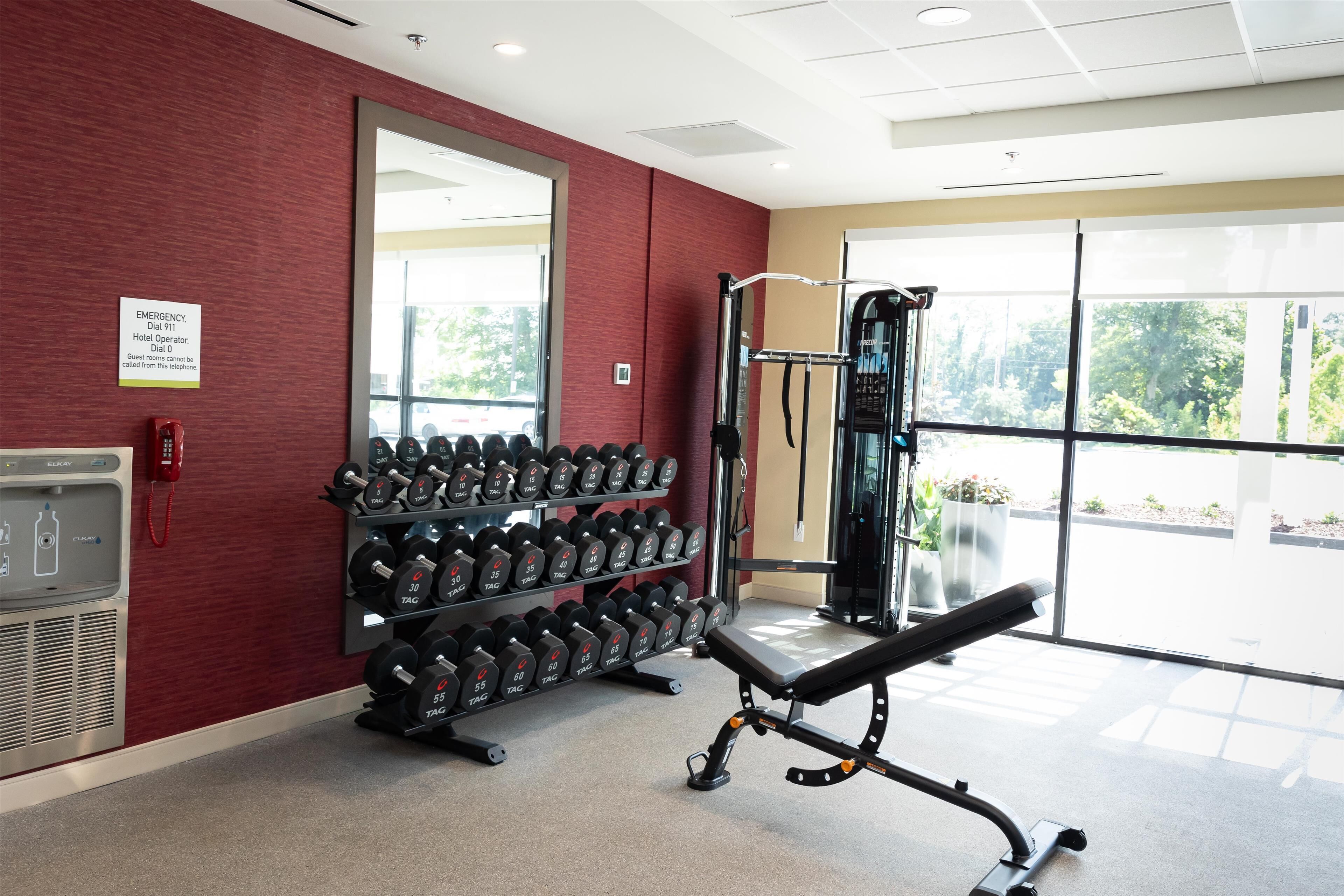 A gym with weightlifting equipment, a water cooler, and a mirror on the wall.