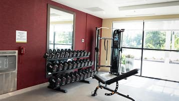 A gym with weightlifting equipment, a water cooler, and a mirror on the wall.
