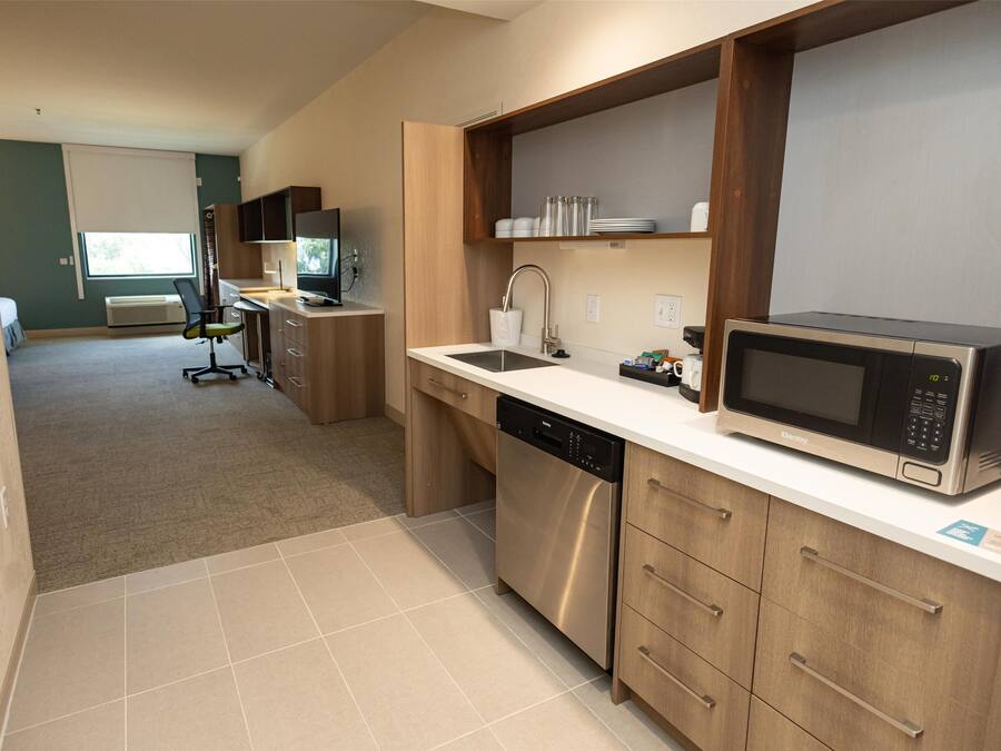 A modern kitchen with stainless steel appliances, wooden cabinets, and a built-in microwave.
