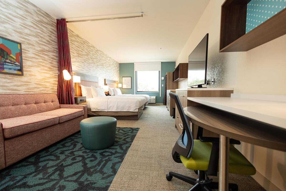 A hotel room with a sofa, a bed, a desk, and a bathroom.