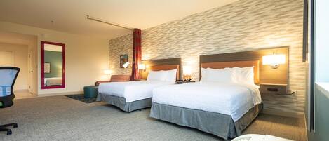 A hotel room with two beds, a desk, and a chair.
