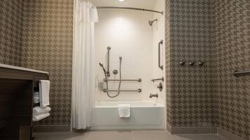 A modern bathroom with a walk-in shower, grab bars, and a towel rack.