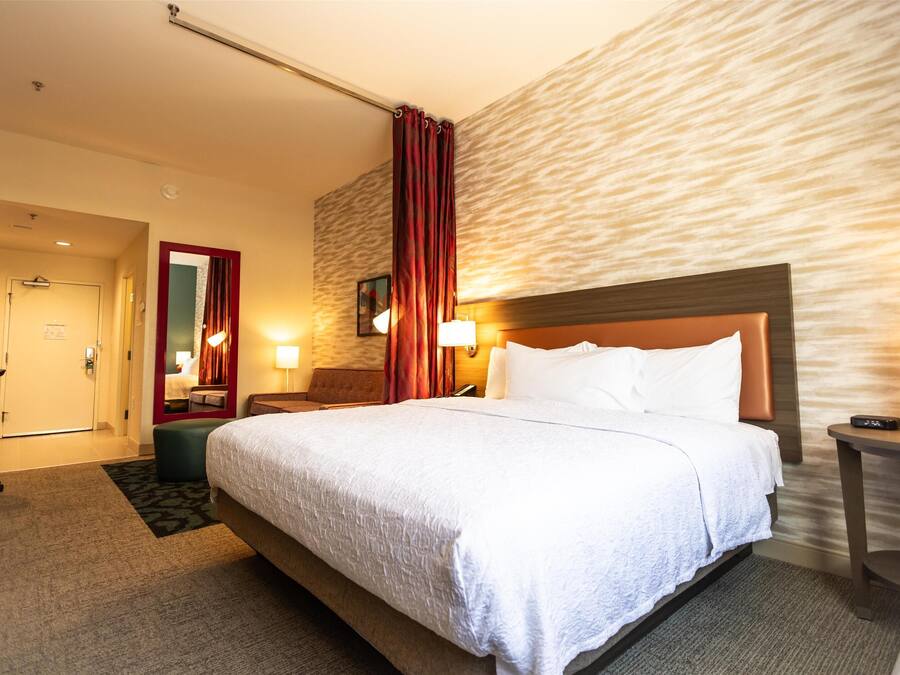 Habitació d'hotel amb un llit gran, una taula de treball, una cadira i un mirall.