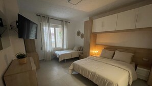 A bedroom with a bed, a bedside table, a TV mounted on the wall, and a window with curtains. - Ruim Modern Familie Appartement in Torrevieja Spanje (Torrevieja)