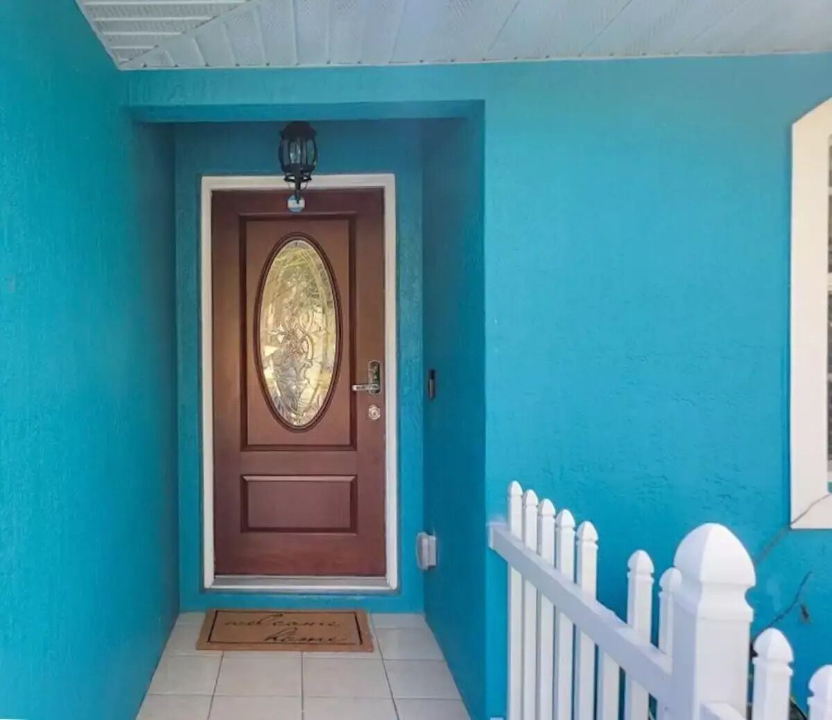 A turquoise house with a brown door featuring a decorative glass panel.