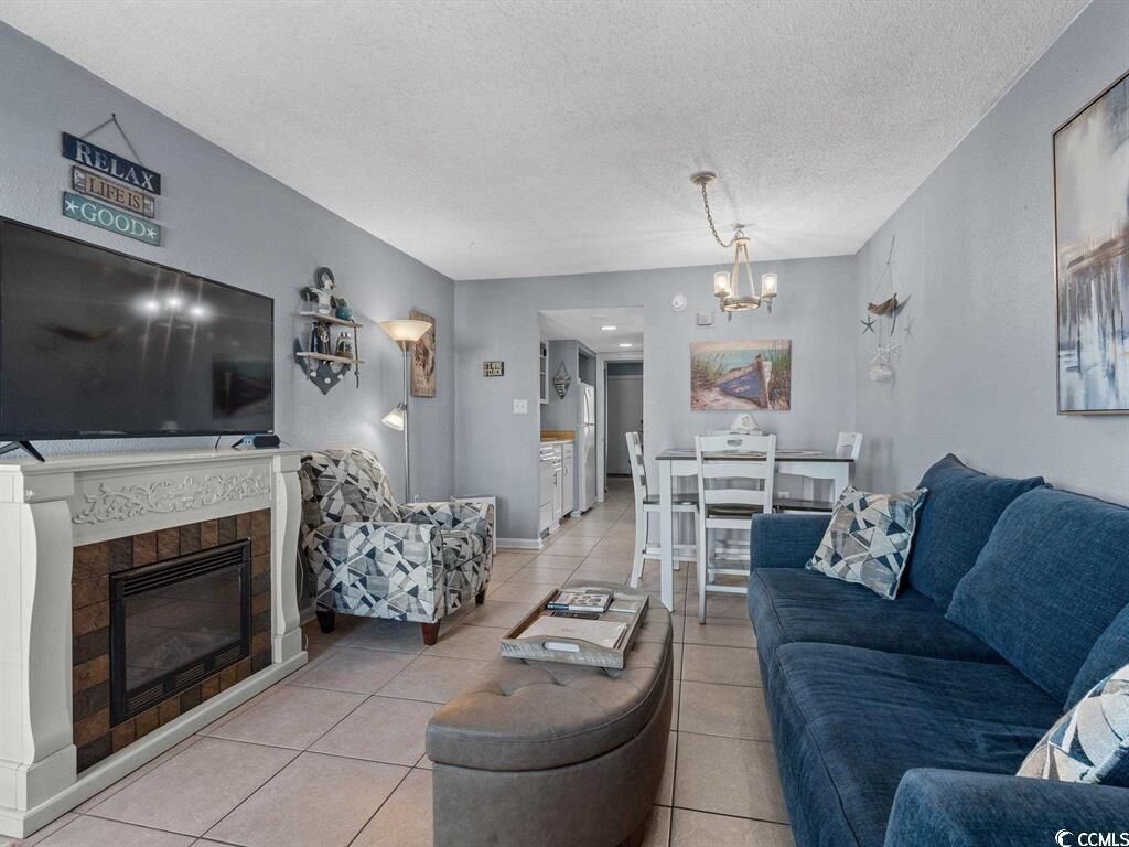 A modern living room with a fireplace, a blue sofa, and a dining area with a white table and chairs.